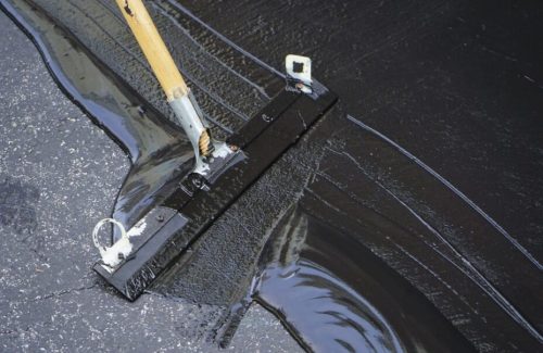 Man sealing asphalt driveway/Sealcoating