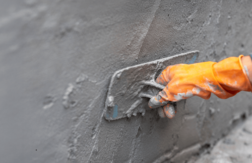 imgi_217_a-worker-in-orange-gloves-smooths-wet-cement-with-a-trowel-for-commercial-stucco-solution